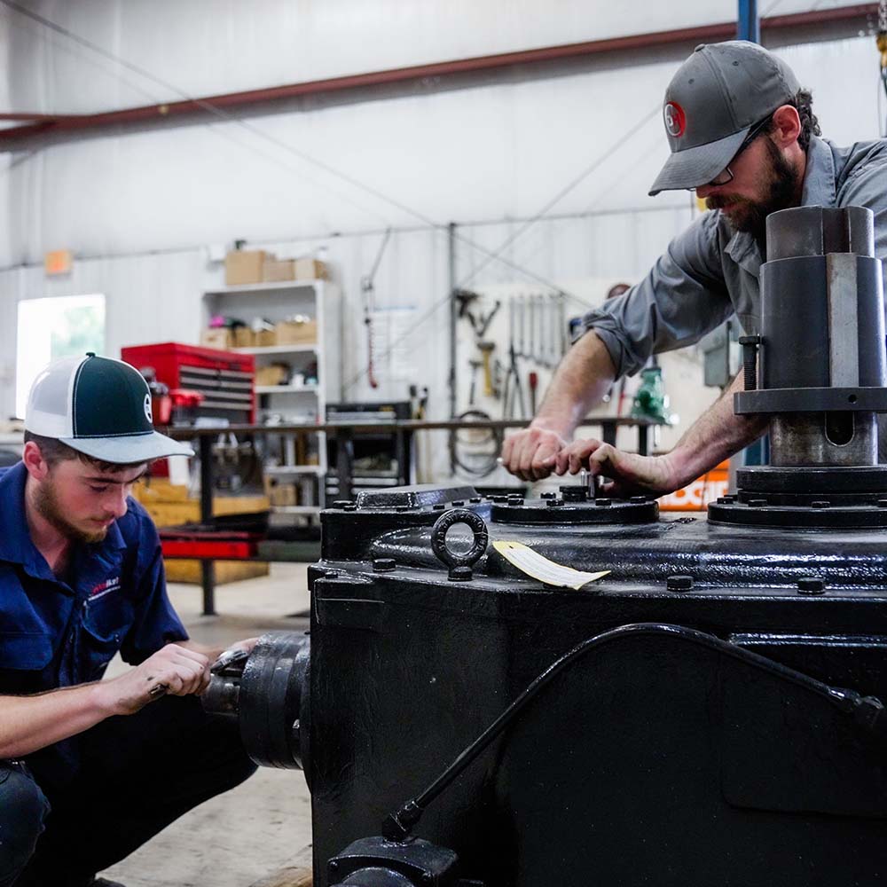 Two men working on vacuum pump and blower repair for DanHart, LLC.