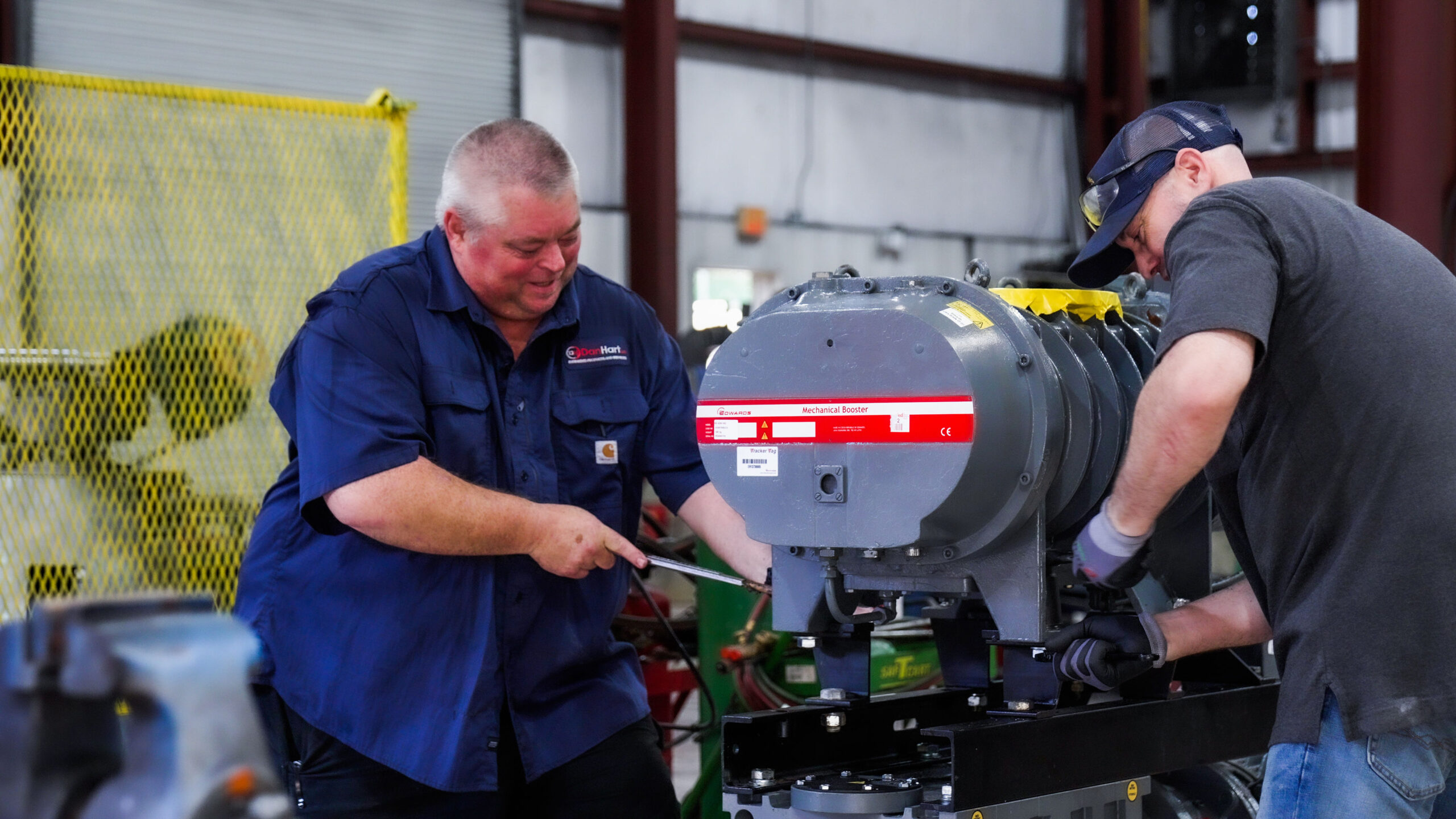 Two men working on vacuum pump and blower repair for DanHart, LLC.